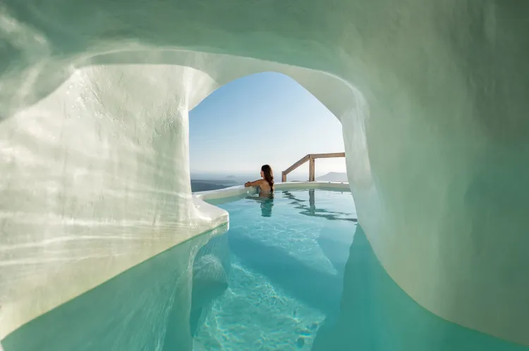 Private pool suite in Santorini overlooking the caldera, framed by cave-style architecture